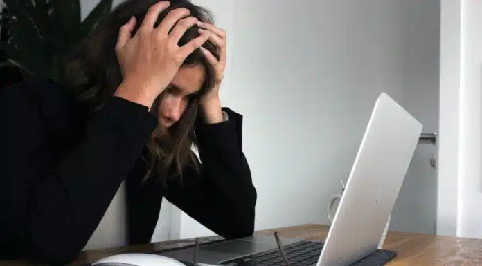 woman in black long sleeve shirt covering her face with her hands