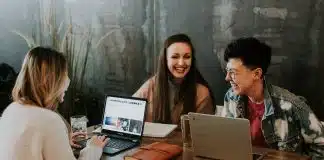 three people sitting in front of table laughing together