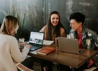 three people sitting in front of table laughing together