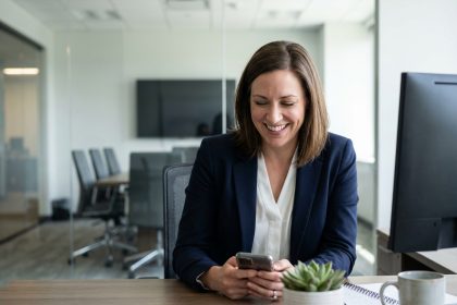 Femme professionnelle souriante utilisant son smartphone au bureau