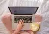 person using MacBook Pro and holding cappuccino