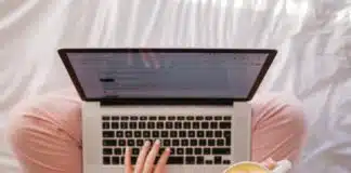 person using MacBook Pro and holding cappuccino